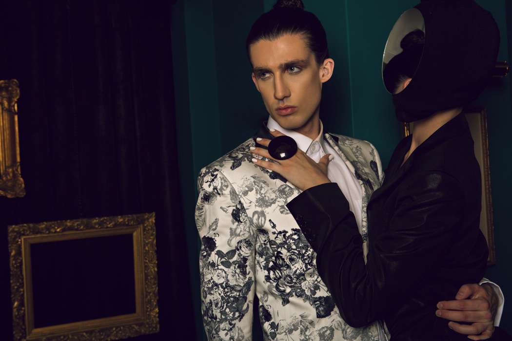 He wears a cotton floral print tuxedo jacket with satin trimmed lapel while she wears a cotton-blend black suit in a liquid finish, both from JIMMY TAILOR. 